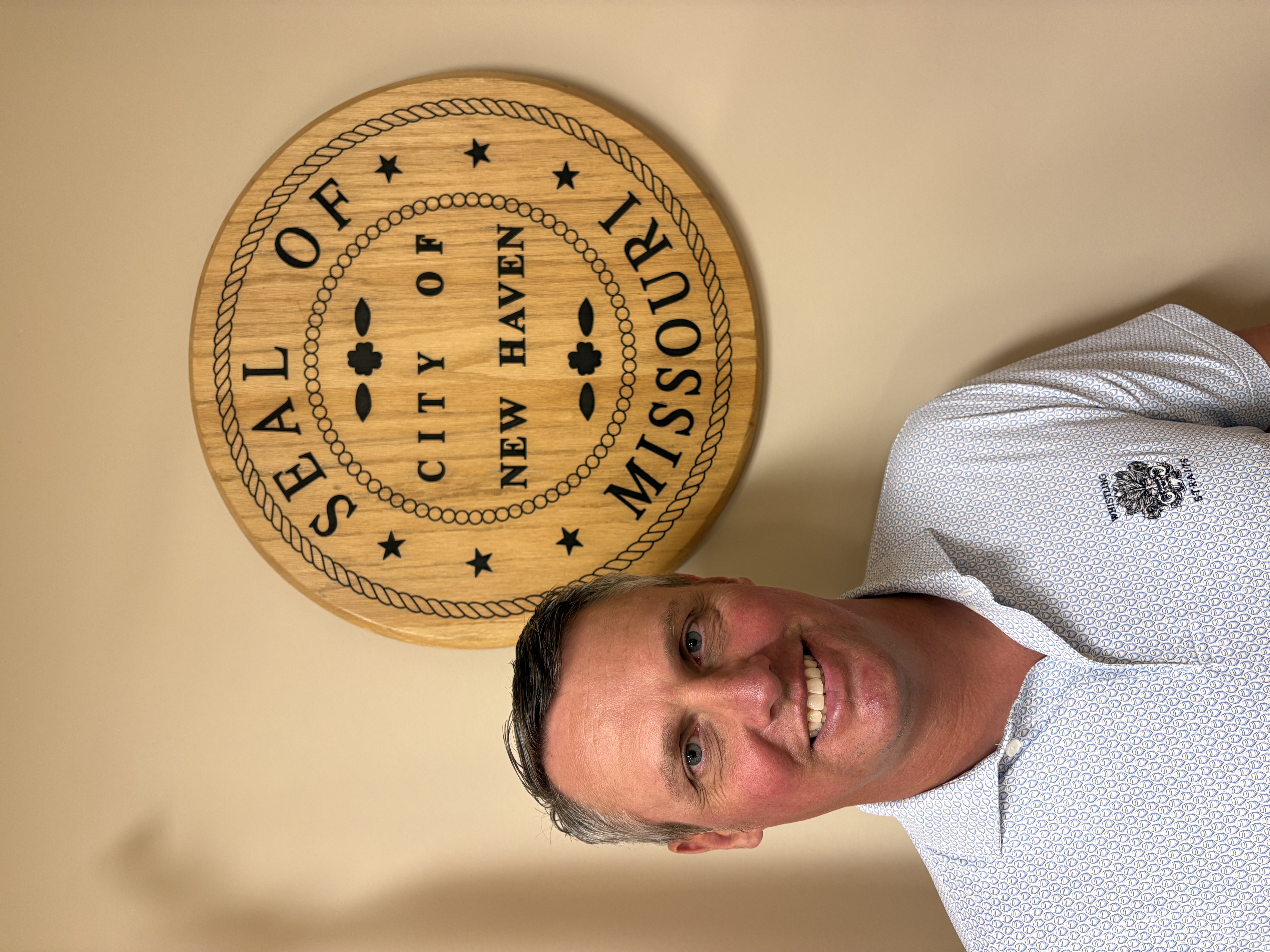Man in front of a wooden seal reading “SEAL OF NEW HAVEN.”